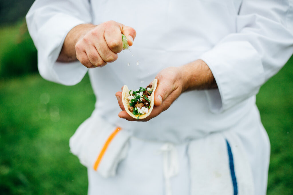 Action shot of a chef squeezing lime onto a taco
