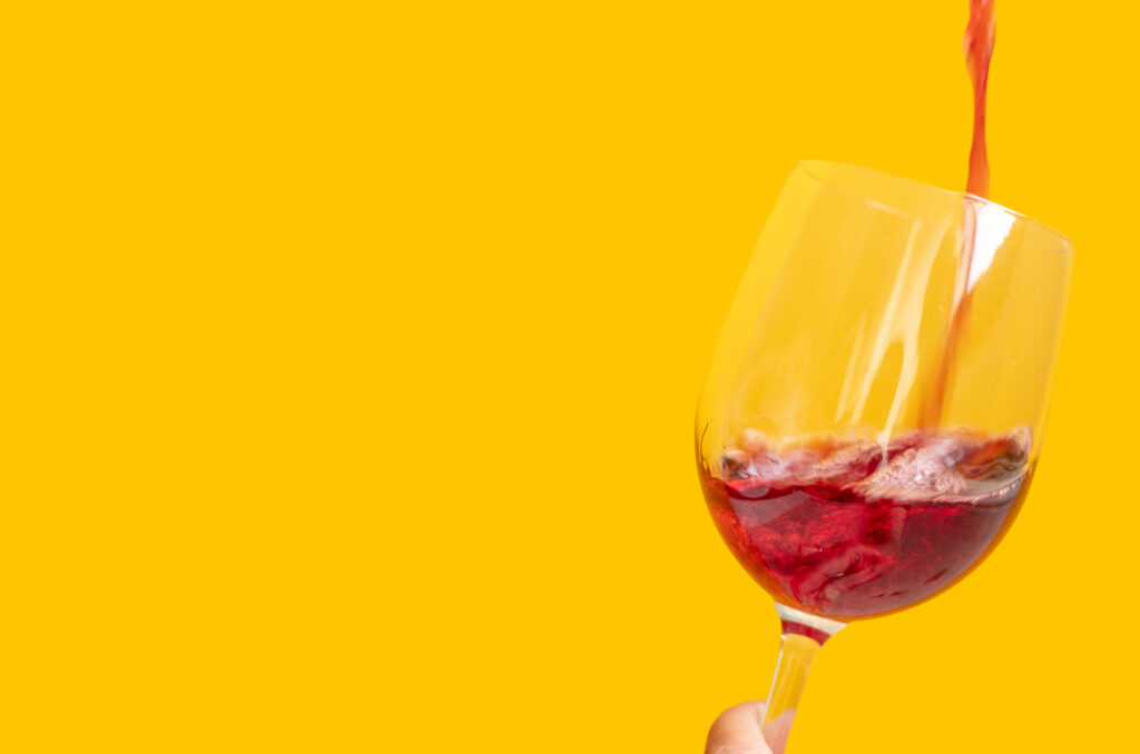 Person pouring a glass of wine for happy hour at elephants delicatessen